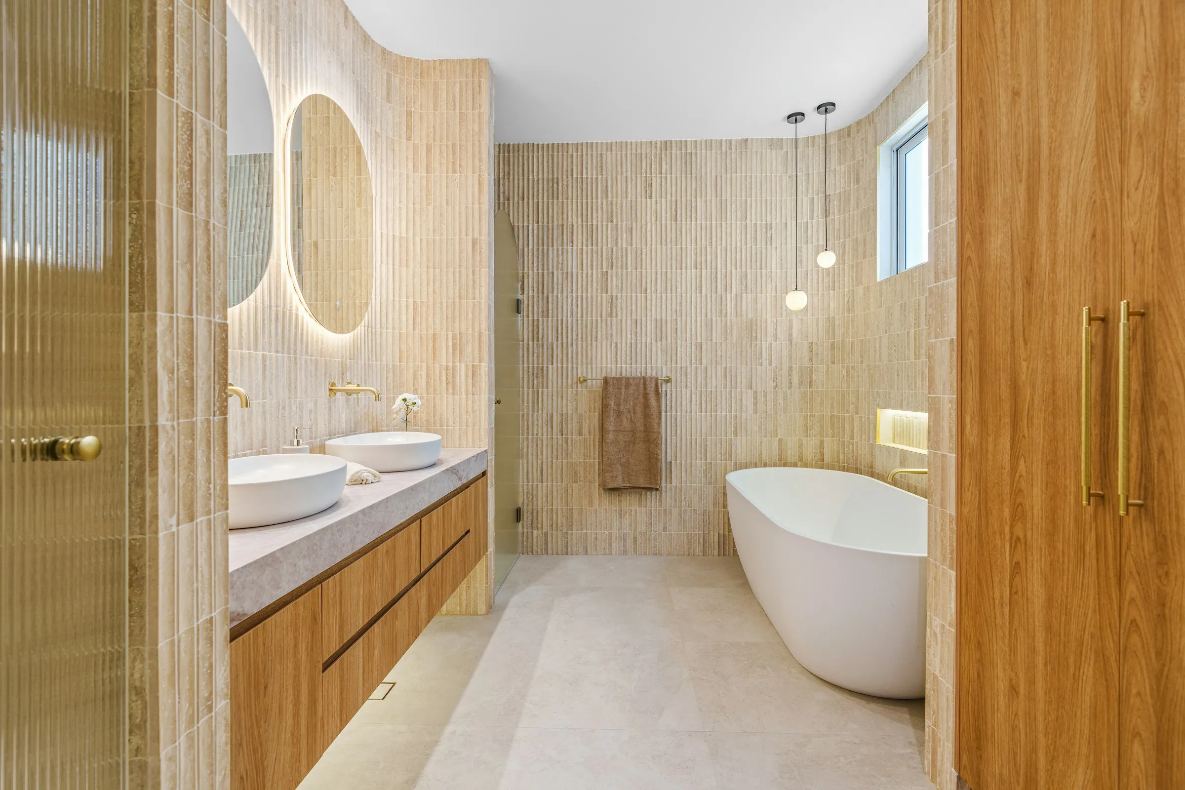 Salle de bain avec double vasque à poser, baignoire îlot et parements clairs